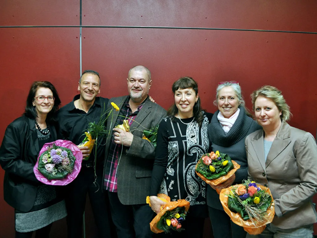Sechs Personen posieren mit Blumensträußen.